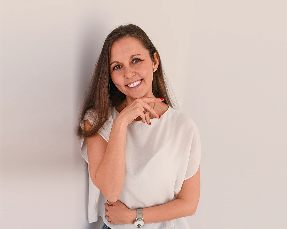 Julia Rimensberger lächelt vor einer neutralen Wand in die Kamera.